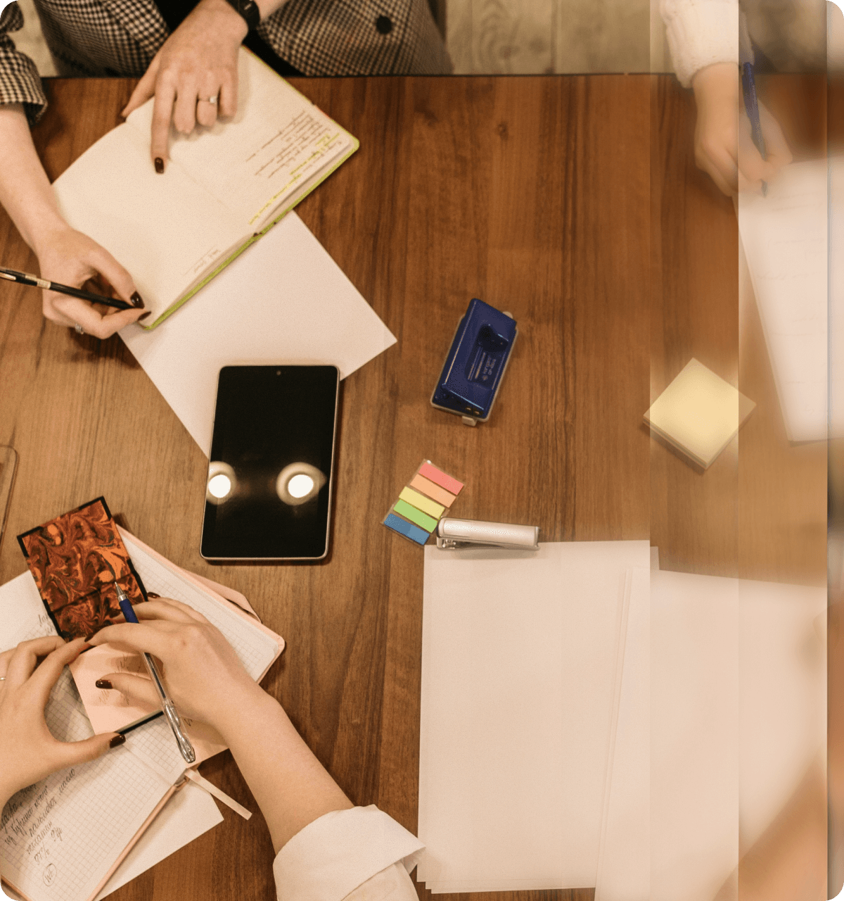 Overhead view of collaborative workspace with team members working together on notebooks and devices